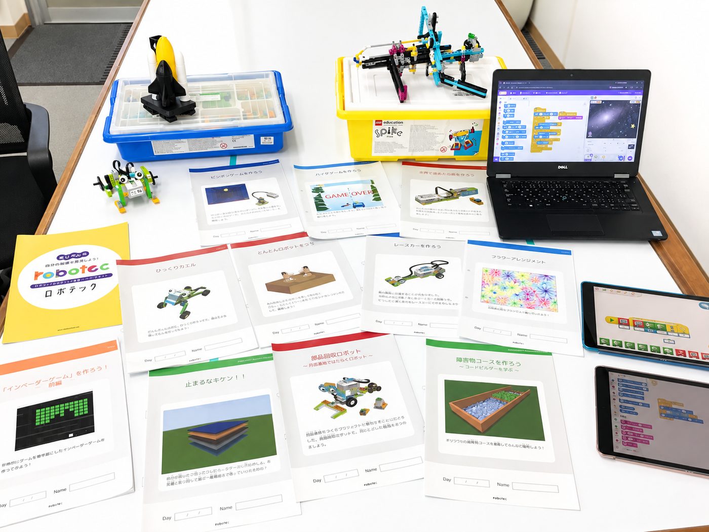レゴ SPIKE プライム・WeDo2.0 の教材ケース、オリジナルテキスト、ノートPC、iPad が並んだロボテックの教材一式