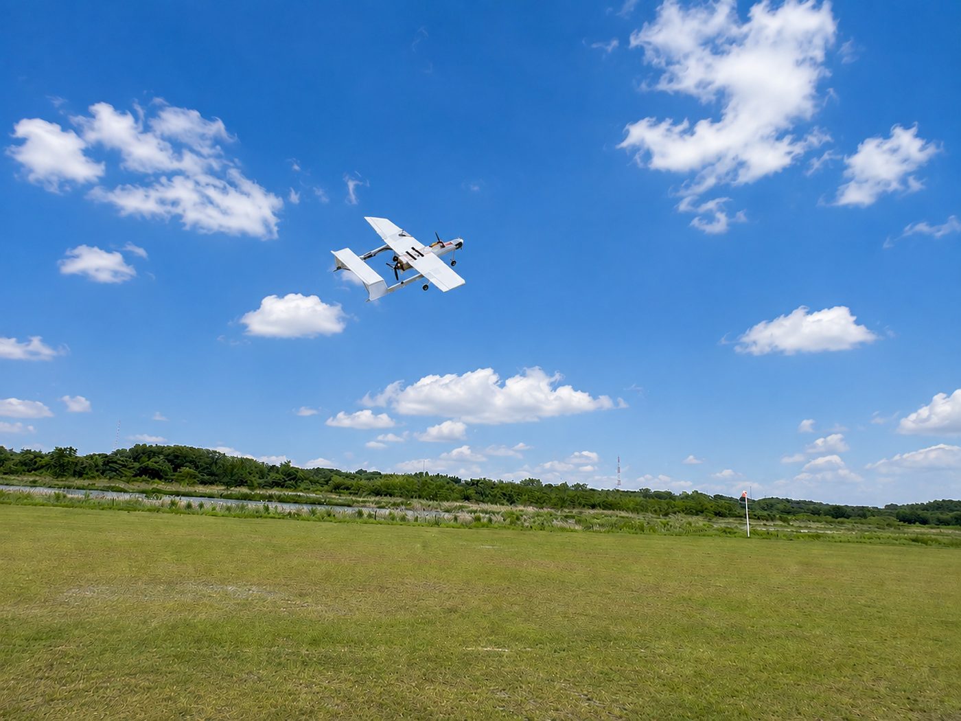 生徒が製作した自作ラジコン飛行機が、青空の下を飛行している様子